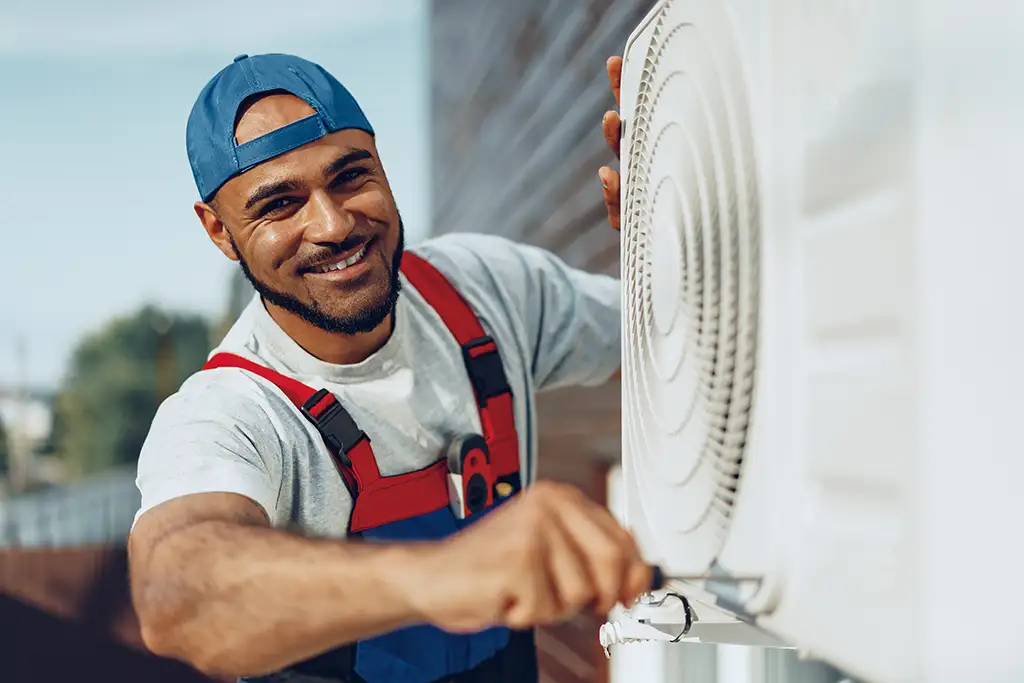 a man in overalls fixing a air conditioner