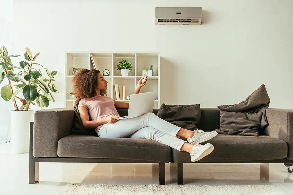 a woman sitting on a couch with a laptop and remote control
