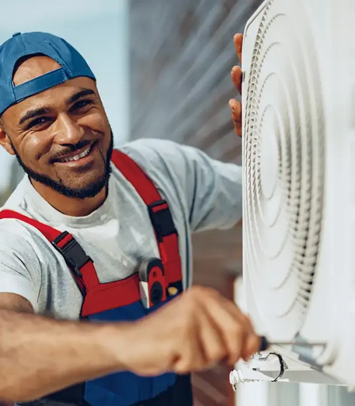 a man in overalls fixing a air conditioner