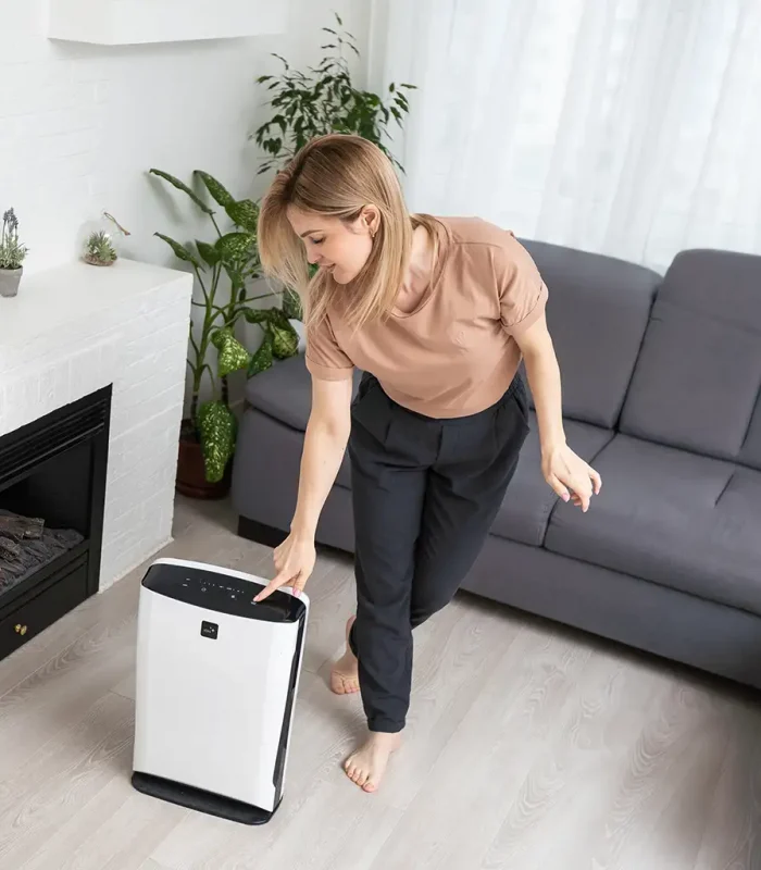 a woman standing in front of a black and white air purifier