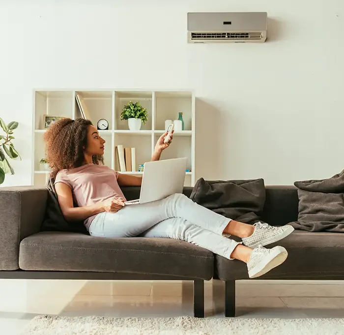 a woman sitting on a couch with a laptop and remote control