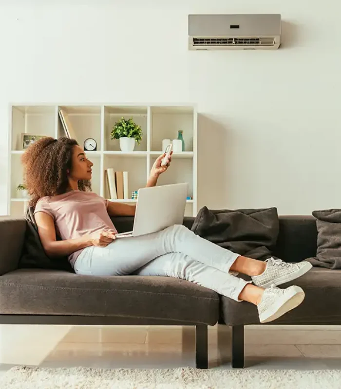 a woman sitting on a couch with a laptop and remote control